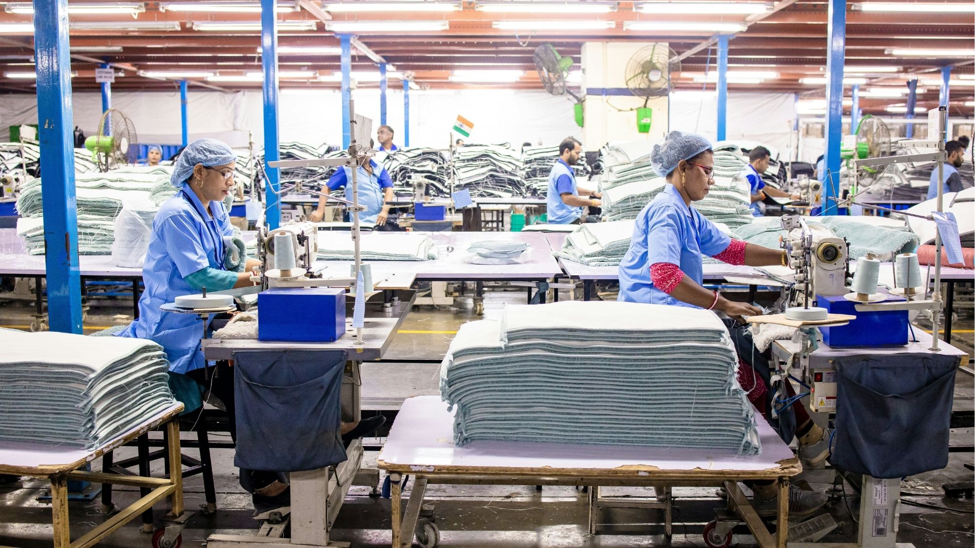 Women inspecting and stitching textiles in a factory as part of quality control.