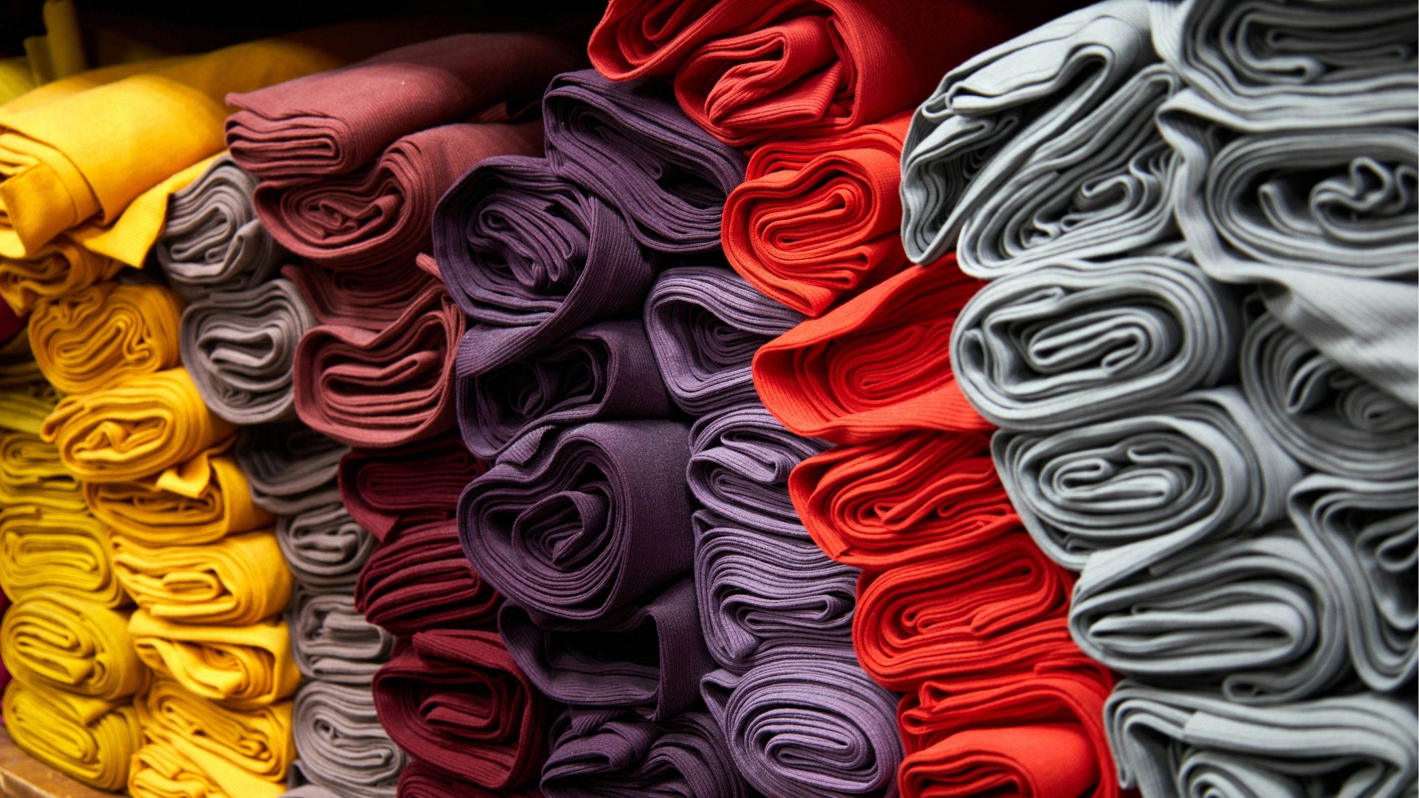Bunch of beautiful fabrics stacked together.